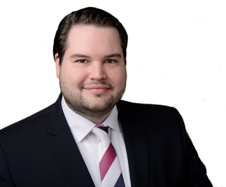 Mann in Anzug mit gestreifter Krawatte, freundliches Lächeln.